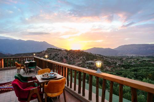 a balcony with a table and chairs and a sunset at Atlas Smile Retreat in Tassa Ouirgane