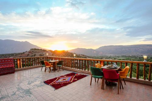 a balcony with tables and chairs and the sunset at Atlas Smile Retreat in Tassa Ouirgane