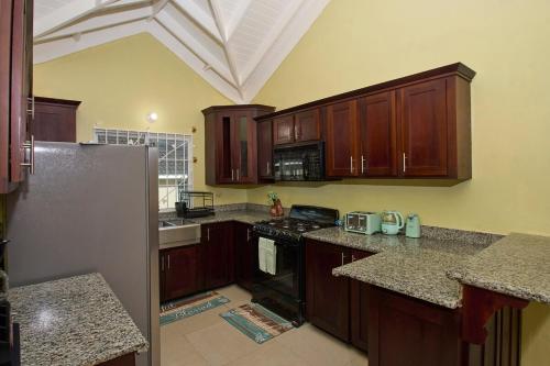 a kitchen with wooden cabinets and a refrigerator at Dejean serenity in Ocho Rios
