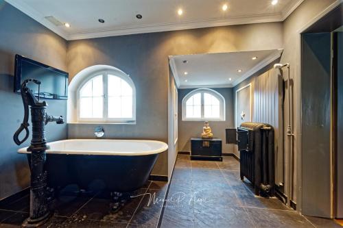 a bathroom with a large tub and a window at Villa Philipp Plein - Designervilla mit Pool in Amriswil
