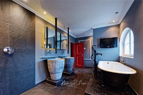 a bathroom with a tub and a sink and a red door at Villa Philipp Plein - Designervilla mit Pool in Amriswil