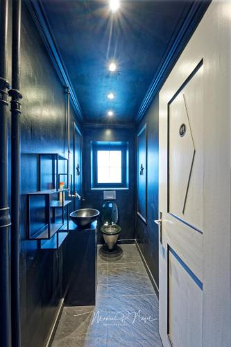 a blue bathroom with a toilet and a door at Villa Philipp Plein - Designervilla mit Pool in Amriswil