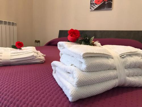 a pile of towels on a bed with red roses at Residenza delle Rose in Lamezia Terme
