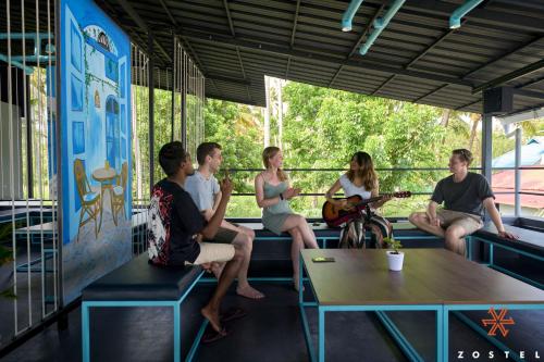 a group of people sitting on benches in a train at Zostel Varkala in Varkala