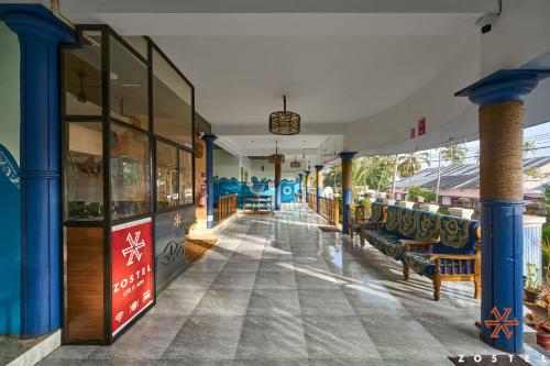 a building with blue columns and benches on a street at Zostel Varkala in Varkala