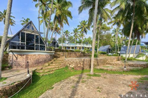 a house with palm trees in front of it at Zostel Varkala in Varkala