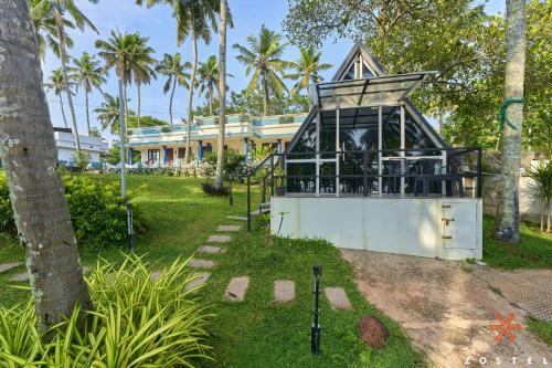 a building in a park with palm trees at Zostel Varkala in Varkala