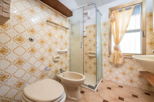 a bathroom with a toilet and a shower and a sink at Villa Mimosa in Porto Pino