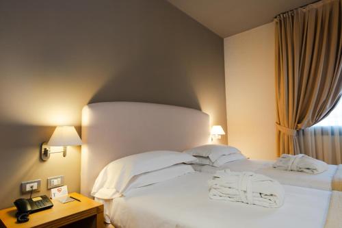 a bedroom with a bed with white sheets and a phone at Hotel Touring in Carpi