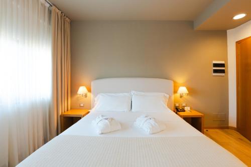 a bedroom with a large white bed with two towels at Hotel Touring in Carpi