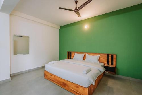 a bedroom with a bed with a green wall at Max residency in Kozhikode