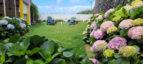 a garden with purple and yellow flowers and chairs at Mosteiros Sea House in Mosteiros