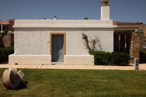 a white building with a blue door and a lighthouse at Porto Kea Suites by Sandglass in Korissia