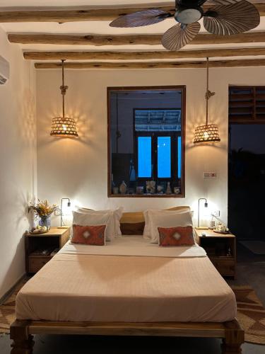 a bedroom with a bed with two tables and a ceiling at Olamanga Beach Villa Adults Only in Jambiani