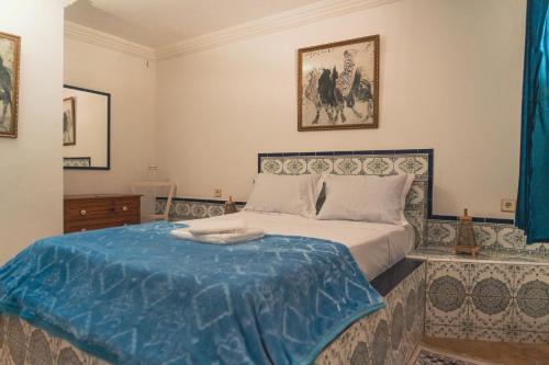 a bedroom with a bed with a blue blanket on it at Roudania Tamraght Ocean View - Private Rooms And Hostel Vibes in Tamraght Ouzdar