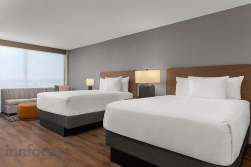 a hotel room with two beds and a couch at Hyatt House Mississauga / Airport Corp Center in Mississauga
