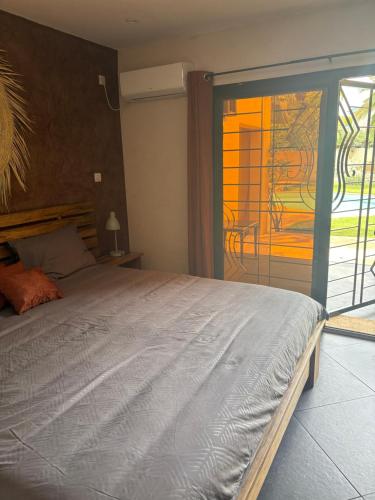 a bedroom with a large bed and a sliding glass door at Chambre indépendante 2 personnes Chez Olivier et Edith in Saly Portudal