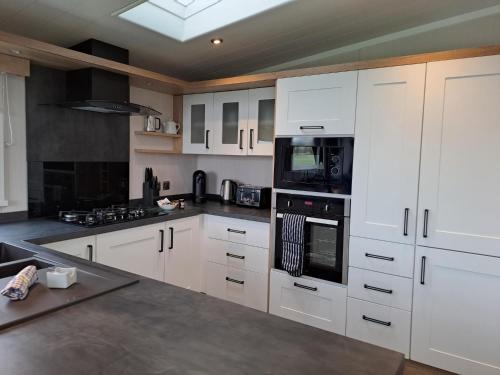 a kitchen with white cabinets and black appliances at Addlethorpe Golf & Country Club, Ingoldmells in Addlethorpe