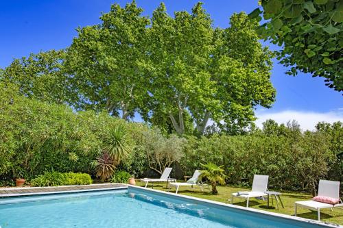 - une piscine avec des chaises et un arbre dans l'établissement Mas La Thèbaïde, à Paradou