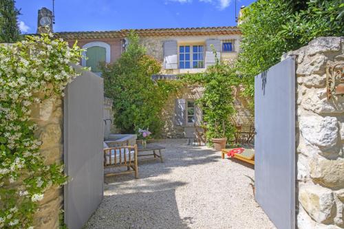 une porte vers un jardin avec une maison dans l'établissement Mas La Thèbaïde, à Paradou
