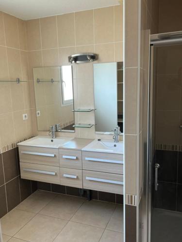 une salle de bain avec deux lavabos et un grand miroir dans l'établissement Charmante VILLA 95 M2, à Vinassan