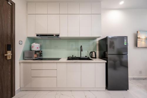 a kitchen with white cabinets and a stainless steel refrigerator at Studio-GH5 - Vinhomes Grand Park - Thu Duc City in Long Bình