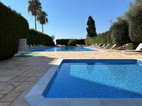 a swimming pool with lounge chairs and a swimming pool at "99 steps to the beach" Beachfront apartment with Kids Room, Pool & 2 Workspaces in Limassol