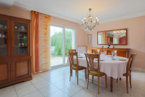 une salle à manger avec une table, des chaises et un lustre dans l'établissement Petite Palmeraie proche plage, à Binic