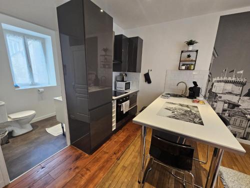 Il comprend une cuisine équipée d'un comptoir blanc et d'un réfrigérateur noir. dans l'établissement Le Pastel - grand studio rénové, à Angoulême