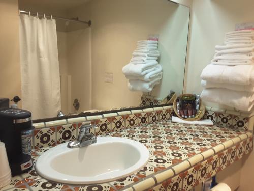 W łazience znajduje się umywalka, lustro i ręczniki. w obiekcie Beaver Creek Inn w mieście Lake Montezuma