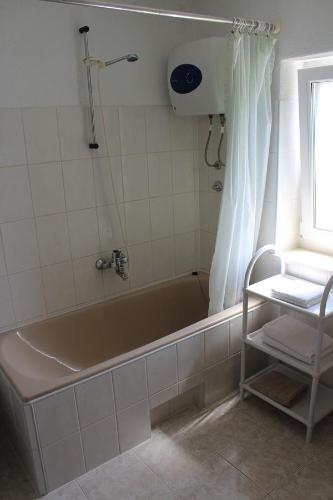 a bathroom with a tub and a shower with a window at Apartments Paula in Splitska