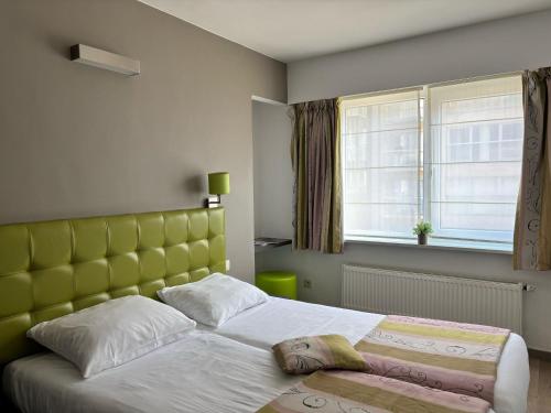1 dormitorio con 1 cama con cabecero amarillo y ventana en Boreas, en Nieuwpoort