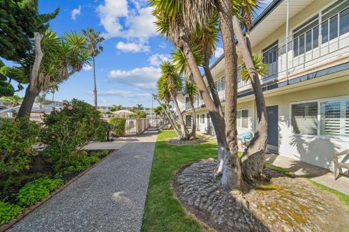a walkway in front of a building with palm trees at 4950 Sandyland Road #127 condo in Carpinteria