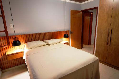 a bedroom with a large white bed with two pillows at Otima Chacara com lazer completo, pet friendly in Carmo