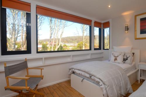 a bedroom with windows and a bed and a chair at Cliff Top - Bubbling Springs in Wemyss Bay