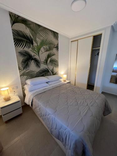 a bedroom with a large bed with a tropical wallpaper at Playamarina 1 Reception in Cabo Roig