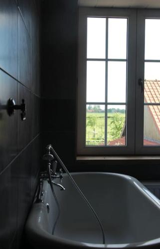 a bathroom with a bath tub and two windows at den overkant in Diksmuide