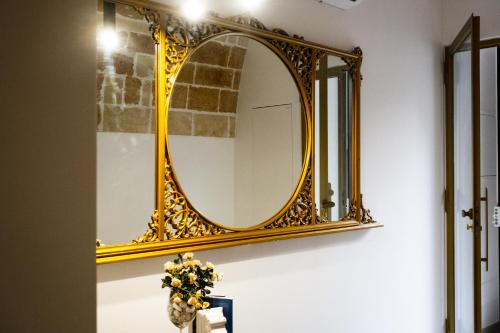 a gold mirror on a wall with flowers in a vase at MAGNIFICAT luxury rooms in Matera
