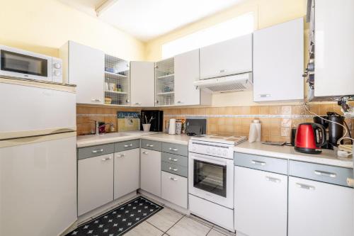 une cuisine blanche avec des armoires et des appareils blancs dans l'établissement Appartement 2 personnes A22, à Pornic