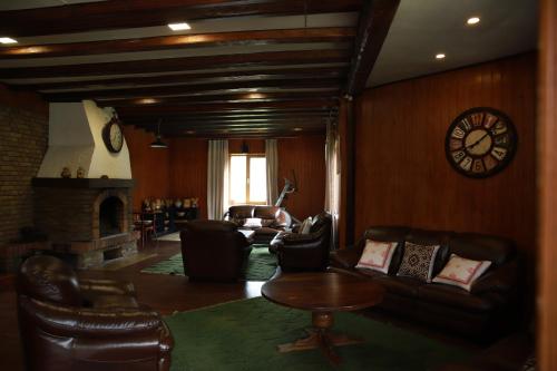 a living room with leather furniture and a clock on the wall at Маєток Ліс і Гори in Bukovel