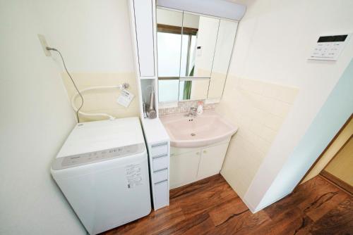 a small bathroom with a washing machine and a sink at Takumi Renovated House Osaka Hirakata with Free Parking in Hirakata