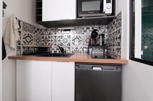 une cuisine avec des armoires blanches et du carrelage noir et blanc dans l'établissement Studio Proche Port Terrasse et Wifi, à Vannes
