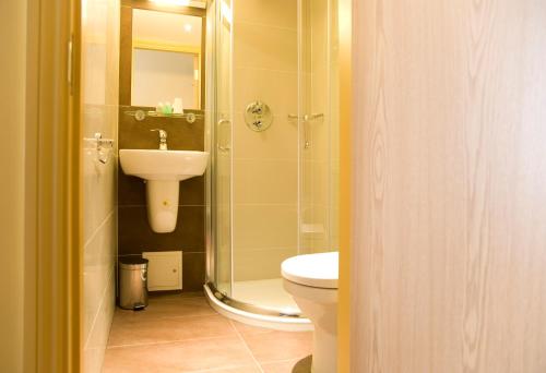 a bathroom with a toilet and a sink and a shower at Rose Park Hotel in London