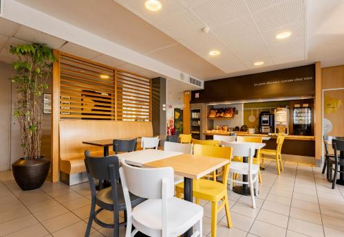 a restaurant with tables and chairs and a bar at B&B HOTEL Valenciennes Marly in Marly