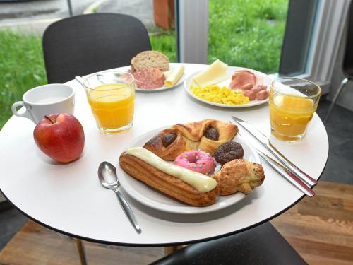 a table with a plate of breakfast foods and drinks at B&B Hotel Trento in Trento