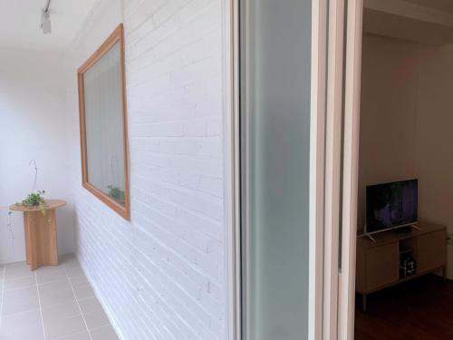 a white brick wall with a mirror and a tv at Mangwon Hangang Park House 3 rooms or one room in Seoul