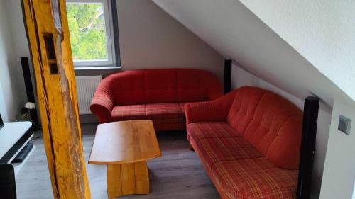 een woonkamer met twee rode banken en een tafel bij Apartment Hollerbusch in Goslar