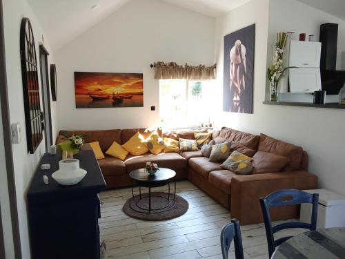 un salon avec un canapé marron et une table dans l'établissement AU PETIT BONHEUR Chez l'habitant 2PERS, à Ferques