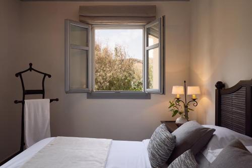 a bedroom with a bed and a window at Porto Kea Suites by Sandglass in Korissia