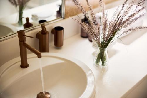 a bathroom sink with water running from a faucet at Porto Kea Suites by Sandglass in Korissia